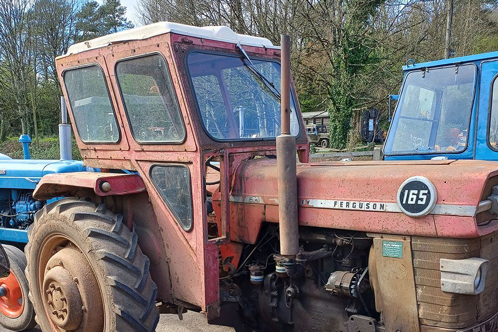 A red tractor is parked next to a blue tractor.
