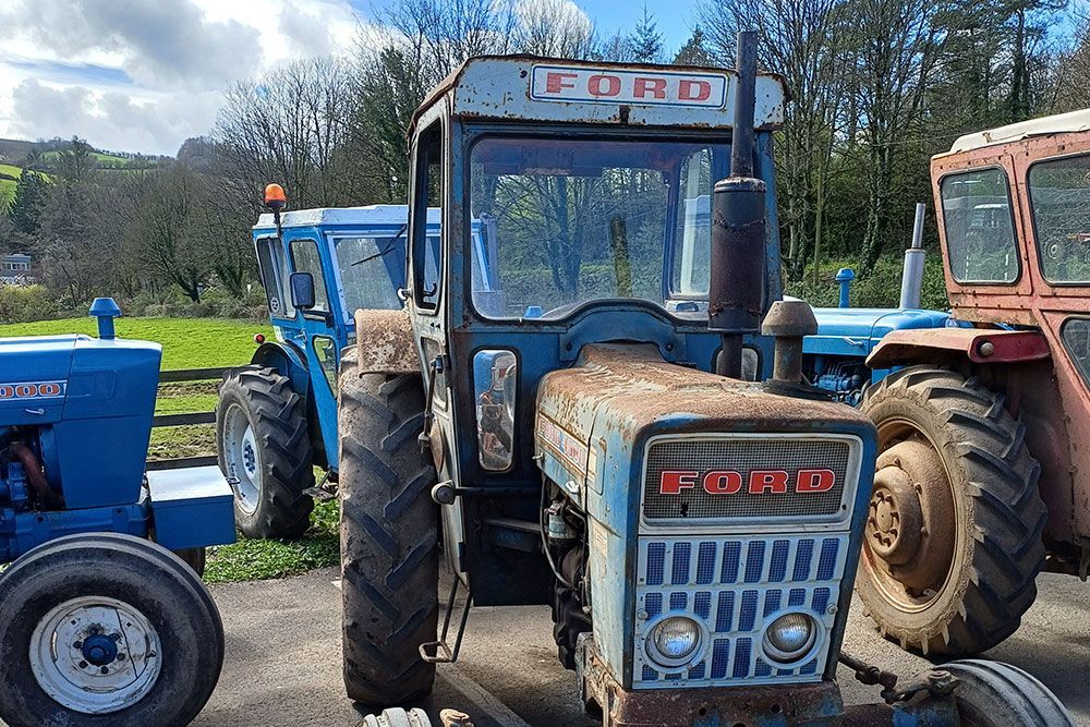 A blue ford tractor is parked next to a red tractor.