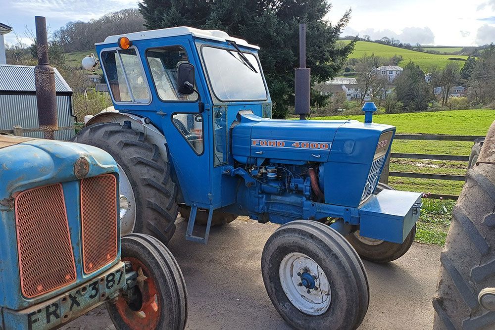 Two blue tractors are parked next to each other in a field.