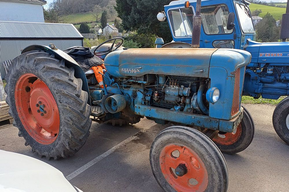 A blue tractor with red wheels is parked next to another blue tractor.