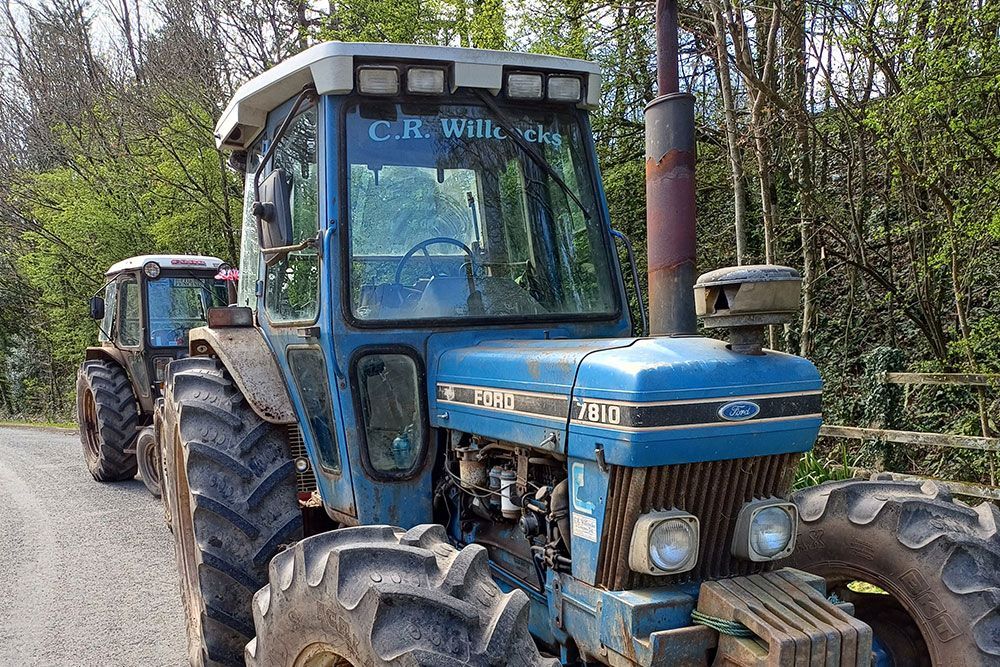 A blue ford tractor is parked on the side of the road.