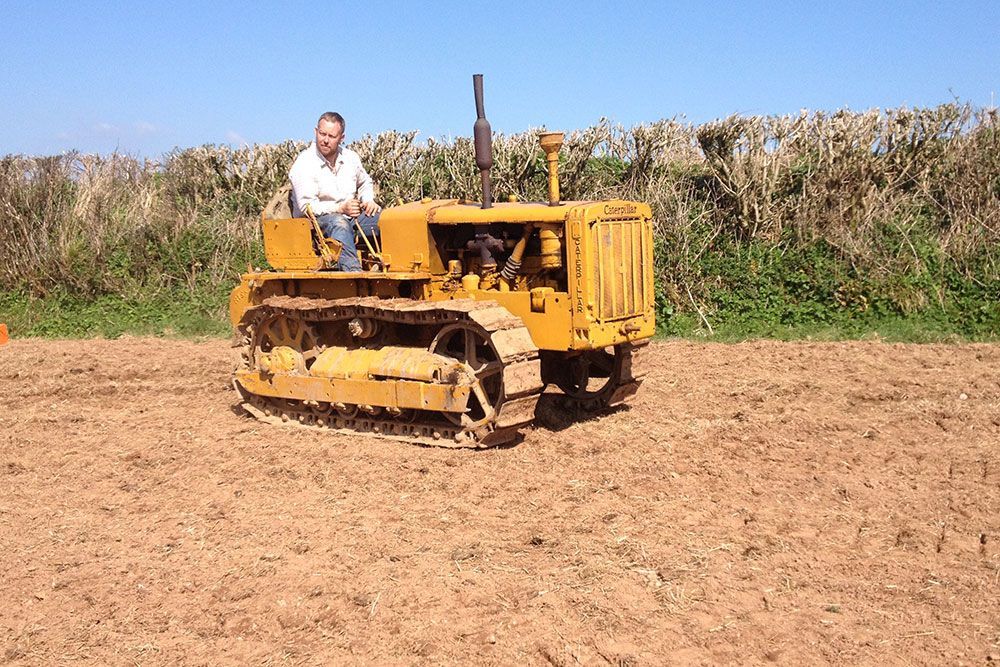 A man is sitting on a yellow bulldozer in a dirt field.