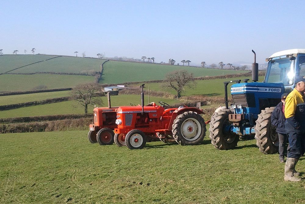 A blue ford tractor is parked next to an orange tractor