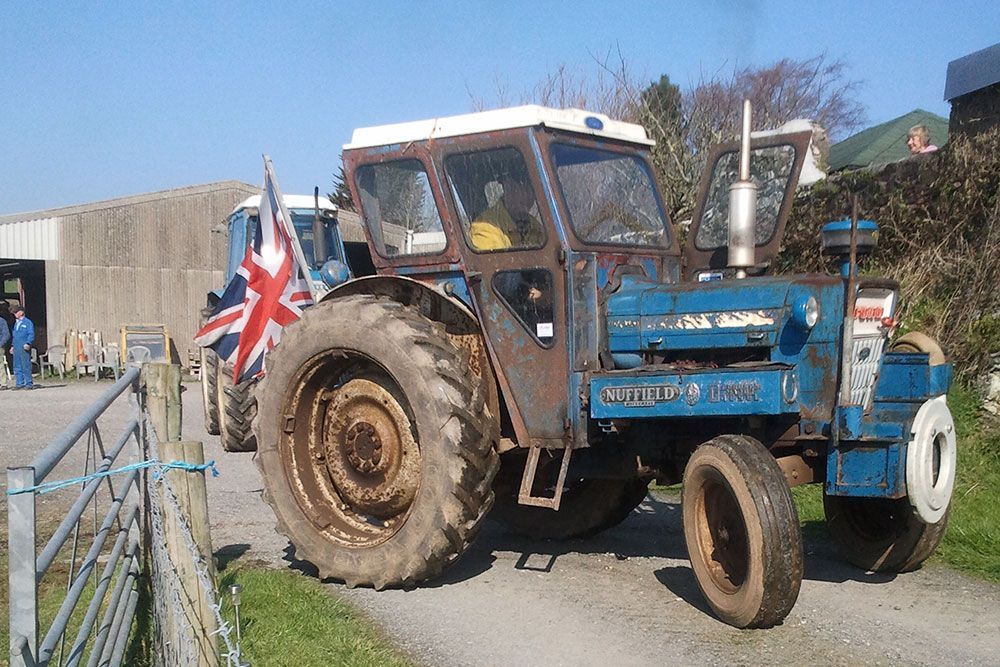 A blue ford tractor is parked on a dirt road