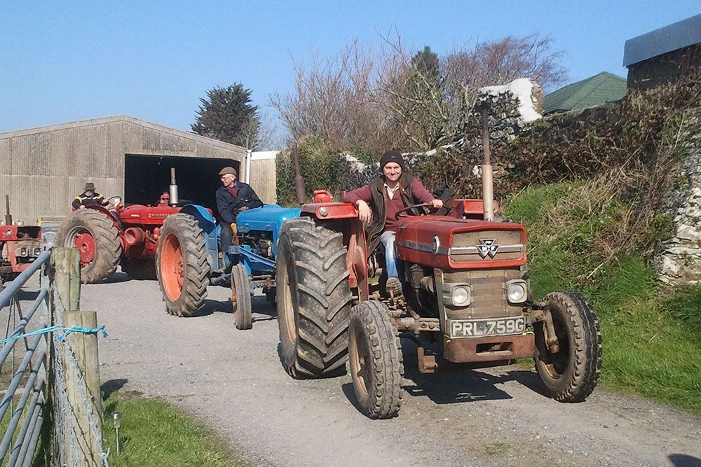 A man sits on a red tractor with a license plate that says phl7490