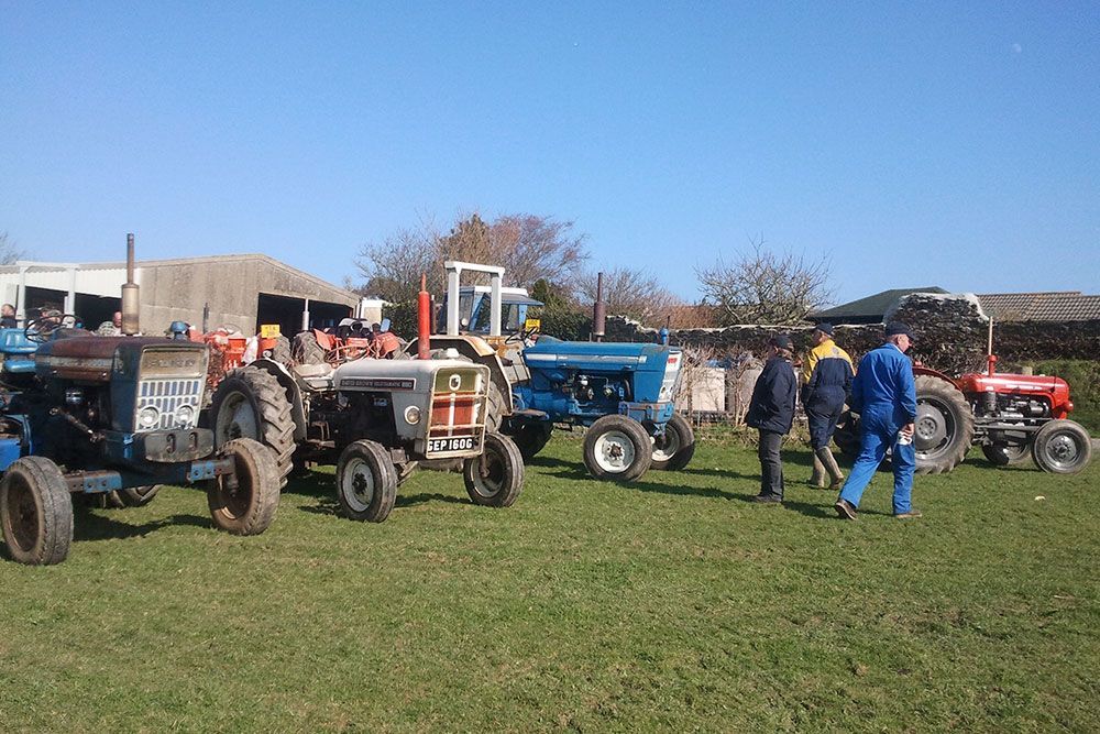 A group of tractors are parked in a grassy field