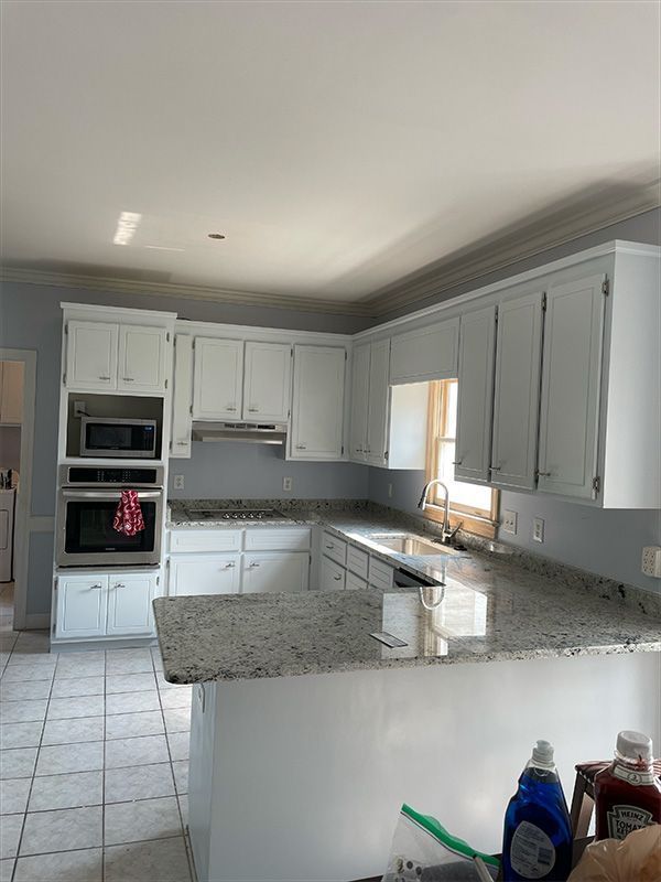 White kitchen with granite countertops, stainless steel sink, and appliances.