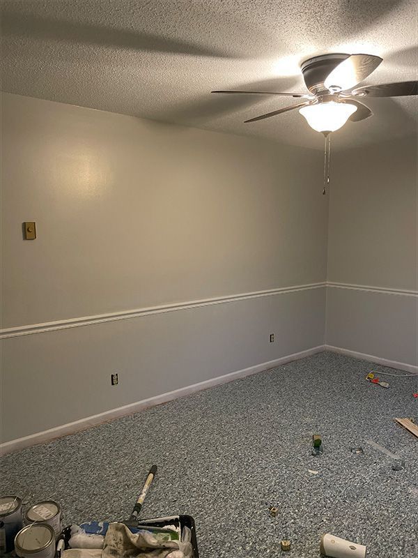 Room with gray walls, white trim, speckled blue carpet, and ceiling fan.