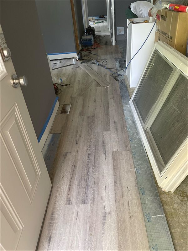 Hallway with light wood-look flooring being installed.