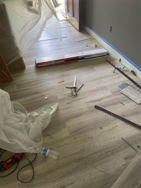 Hallway with gray wood-look flooring being installed; tools and flooring materials are present.