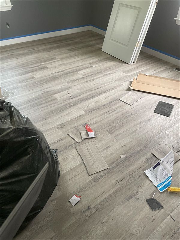 Room with gray wood-look flooring being installed.