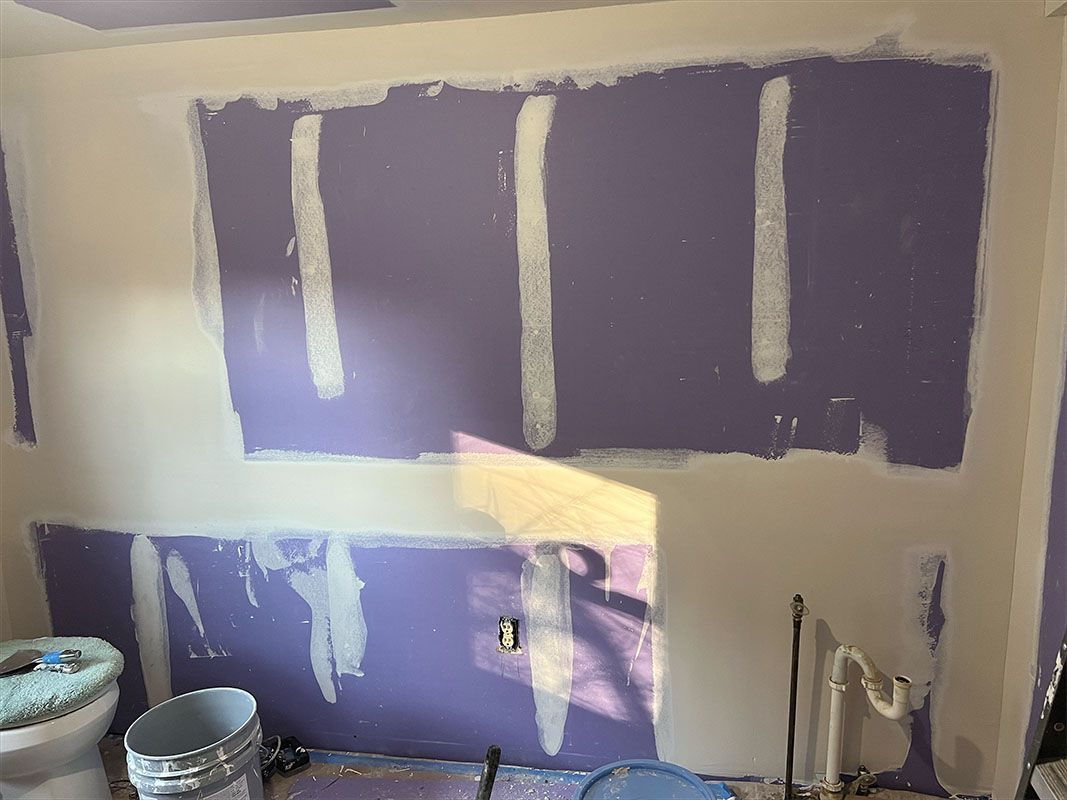 Walls under construction: purple drywall, white tape, unfinished bathroom.
