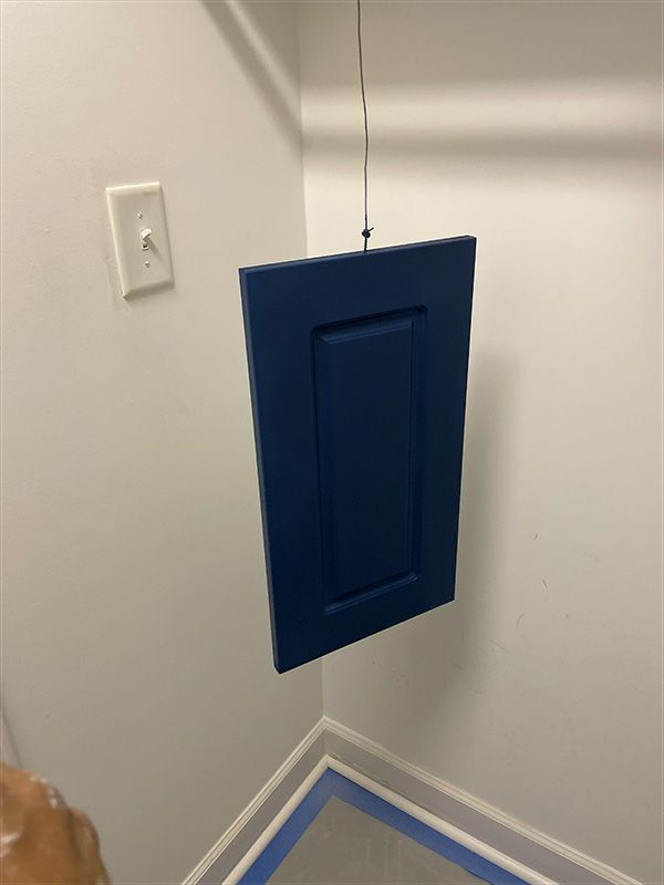Blue painted cabinet door hanging to dry in a corner of a room.