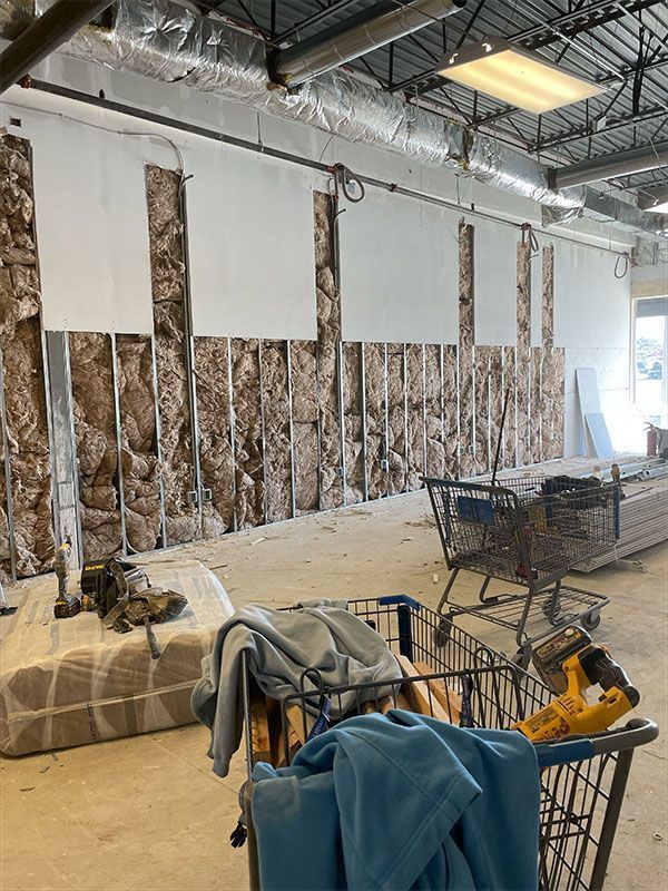 Construction site interior with exposed wall insulation, drywall, shopping carts, and tools.