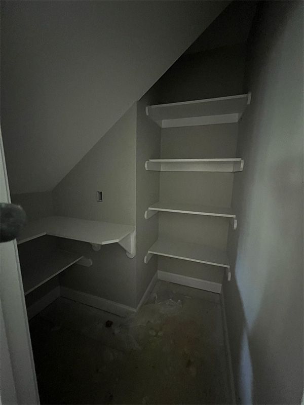 Empty closet with angled ceiling and built-in shelves. Gray walls, white shelves.