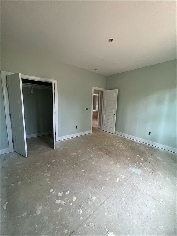 Empty room with pale green walls, open closet, and white doors. 