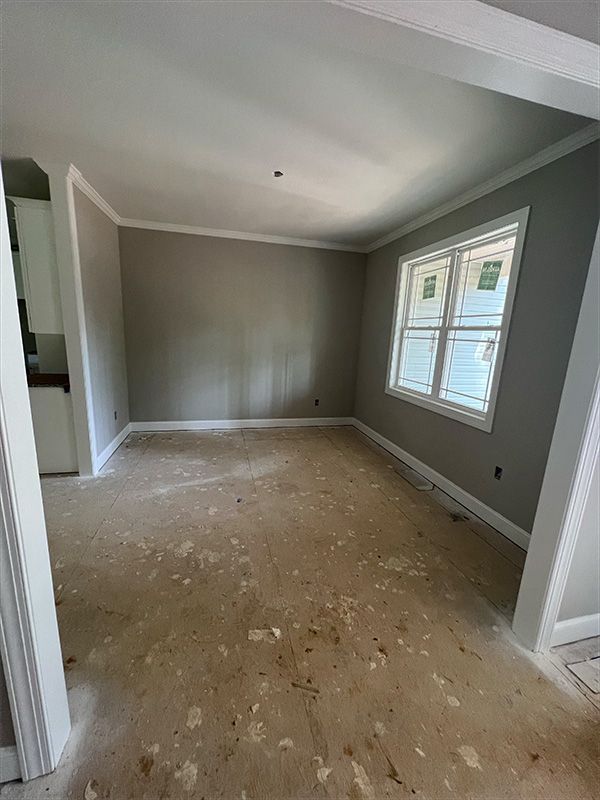Empty room with gray walls, white trim, and a window. 