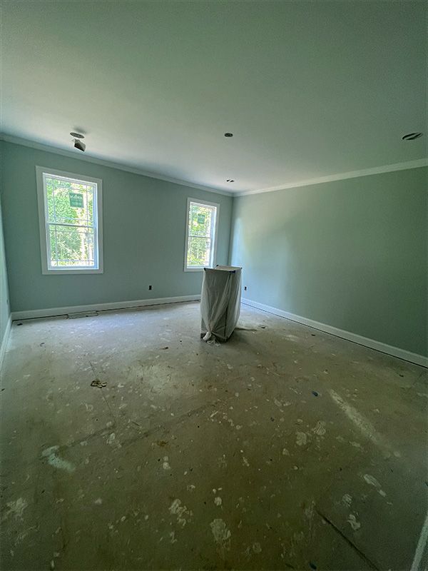 Empty room with mint green walls, two windows, and unfinished floor.