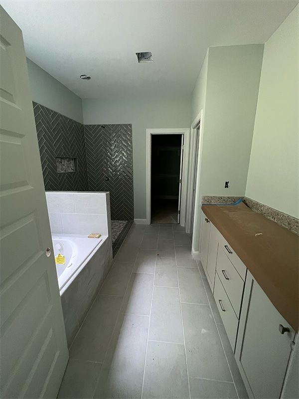 Bathroom with bathtub, shower, long vanity, and gray tile floor. 