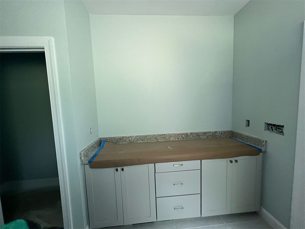Built-in cabinets with a countertop against a pale green wall, next to a doorway.