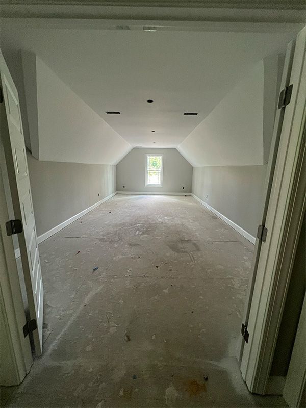 Empty room under construction with sloped ceiling, gray walls, white trim and ceiling.