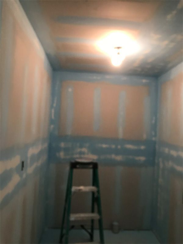 An unfinished room with a ladder; walls are blue and beige. 