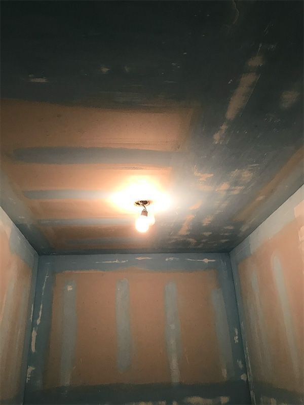 Ceiling with a bare lightbulb, walls show drywall. 