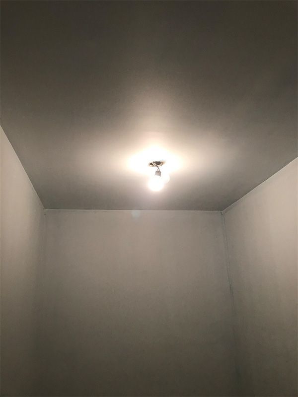A small, empty room with a single light fixture on the ceiling. 