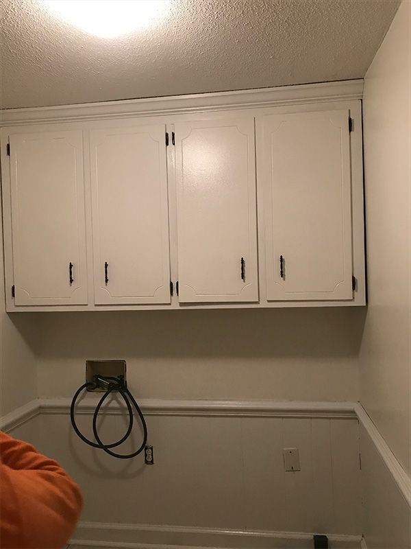 White cabinets mounted on a wall in a room with white paneling and a ceiling.