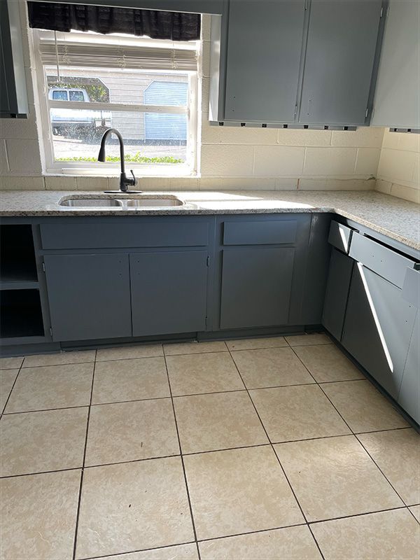 Kitchen with grey cabinets, white countertops, and beige tiled floor. 
