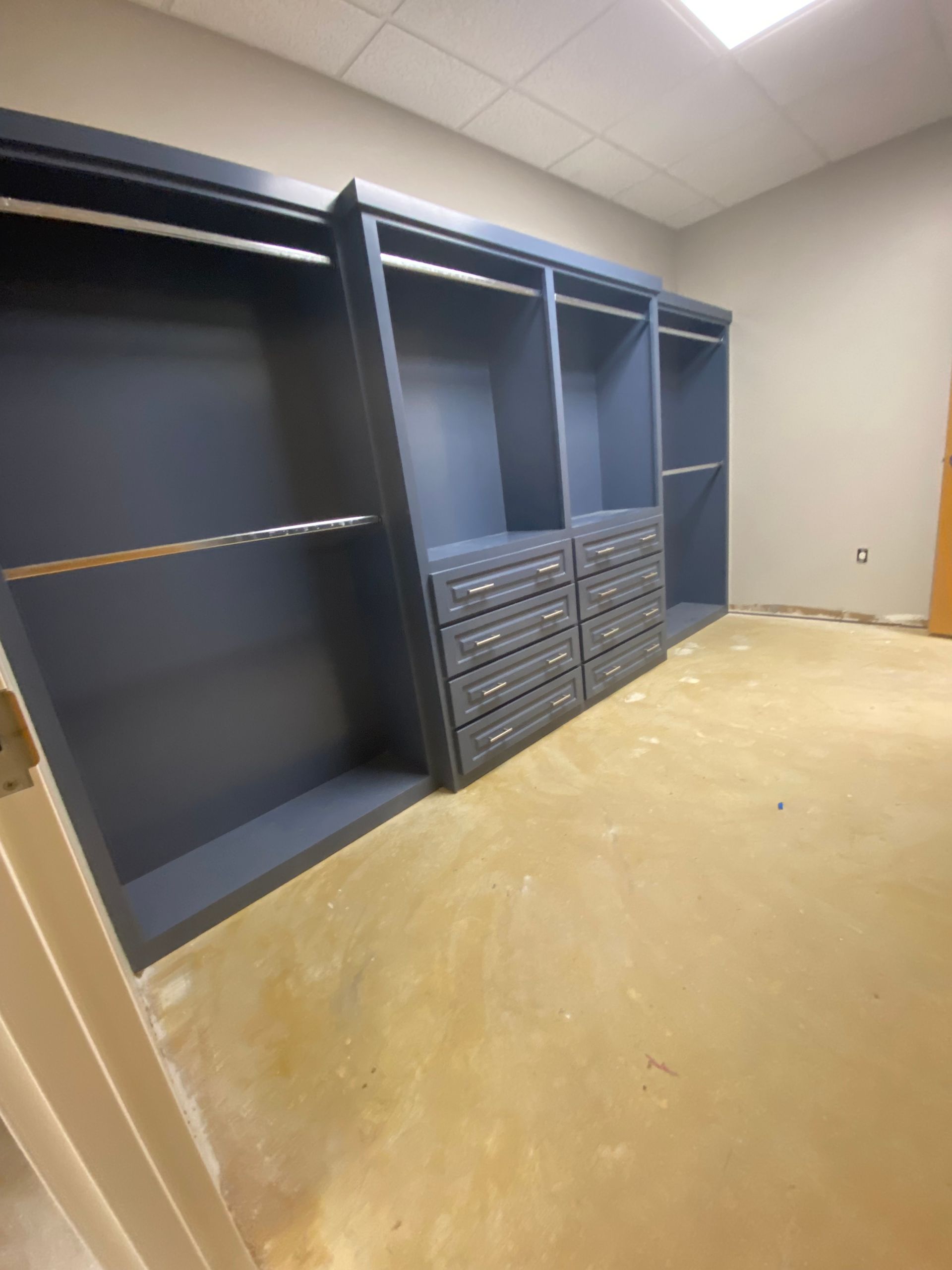 Modern kitchen with gray island, white countertops, and wooden beam.