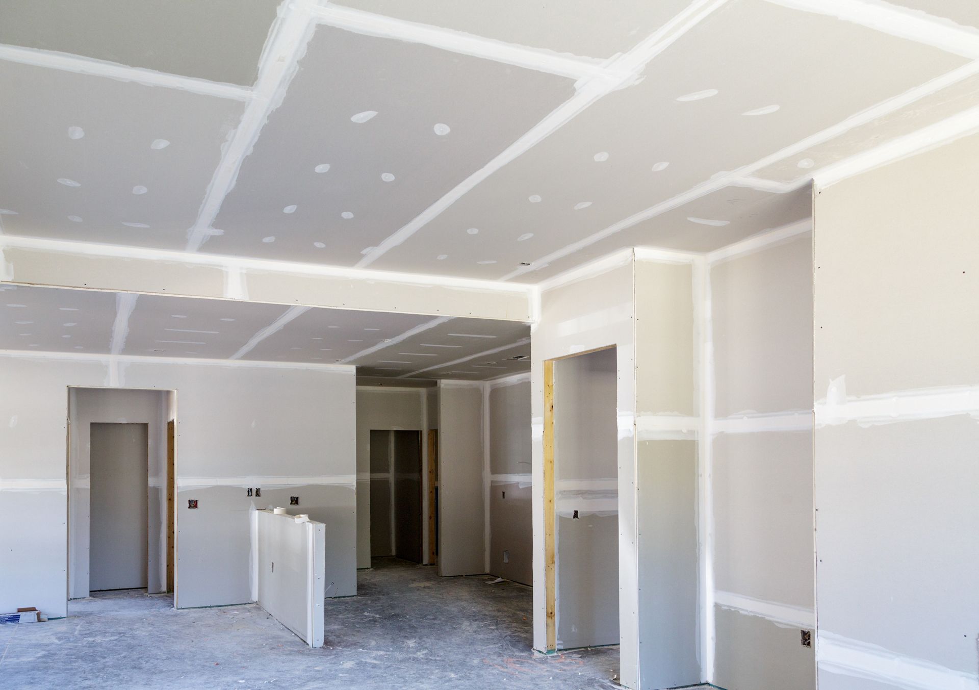 Interior of a room under construction, with drywall installed on walls and ceiling.