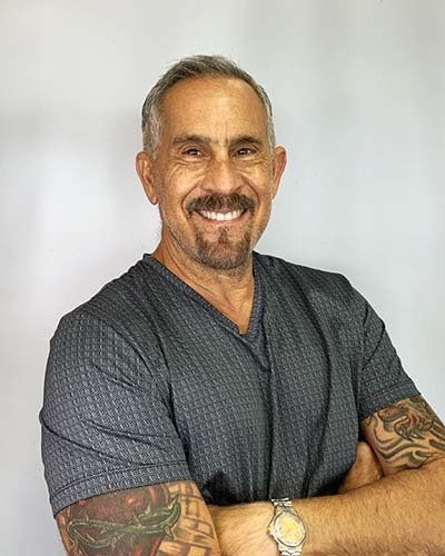 a man with tattoos on his arms is smiling and wearing a watch .