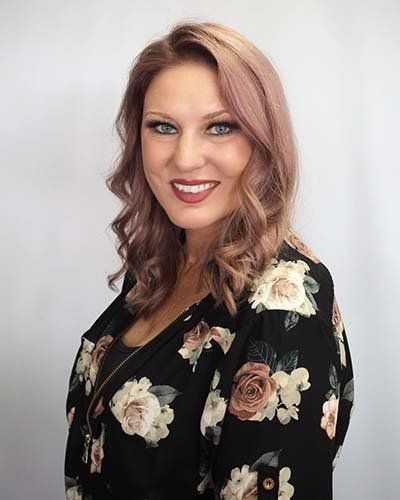 a woman wearing a black floral shirt is smiling for the camera .