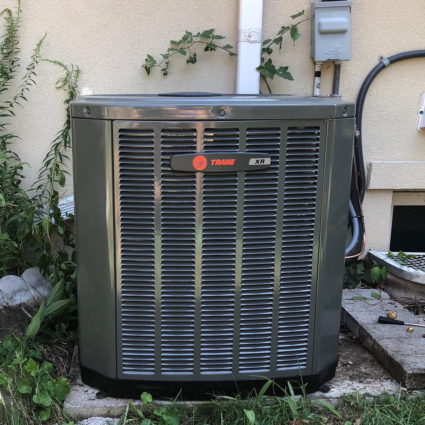 A man is working on an air conditioner with a screwdriver.