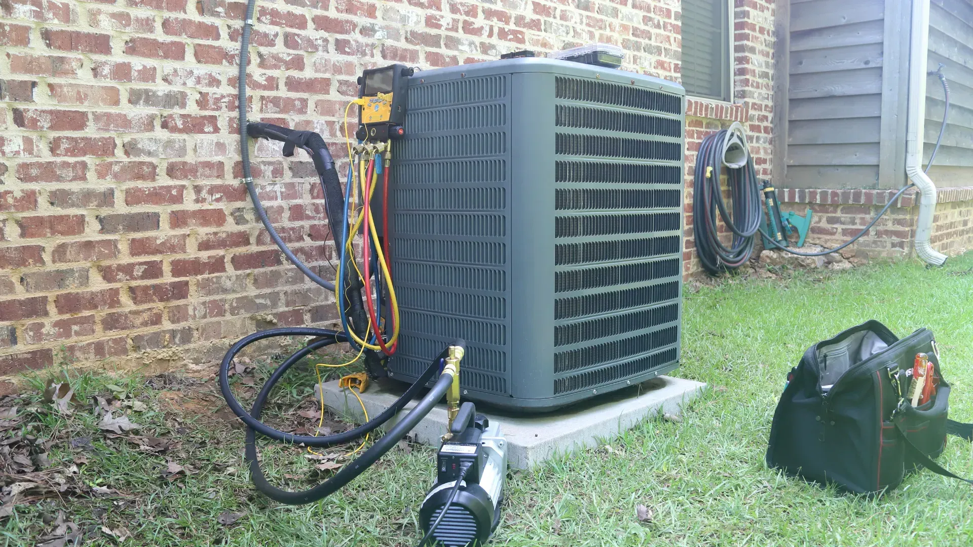 An air conditioner is being installed on the side of a brick building.