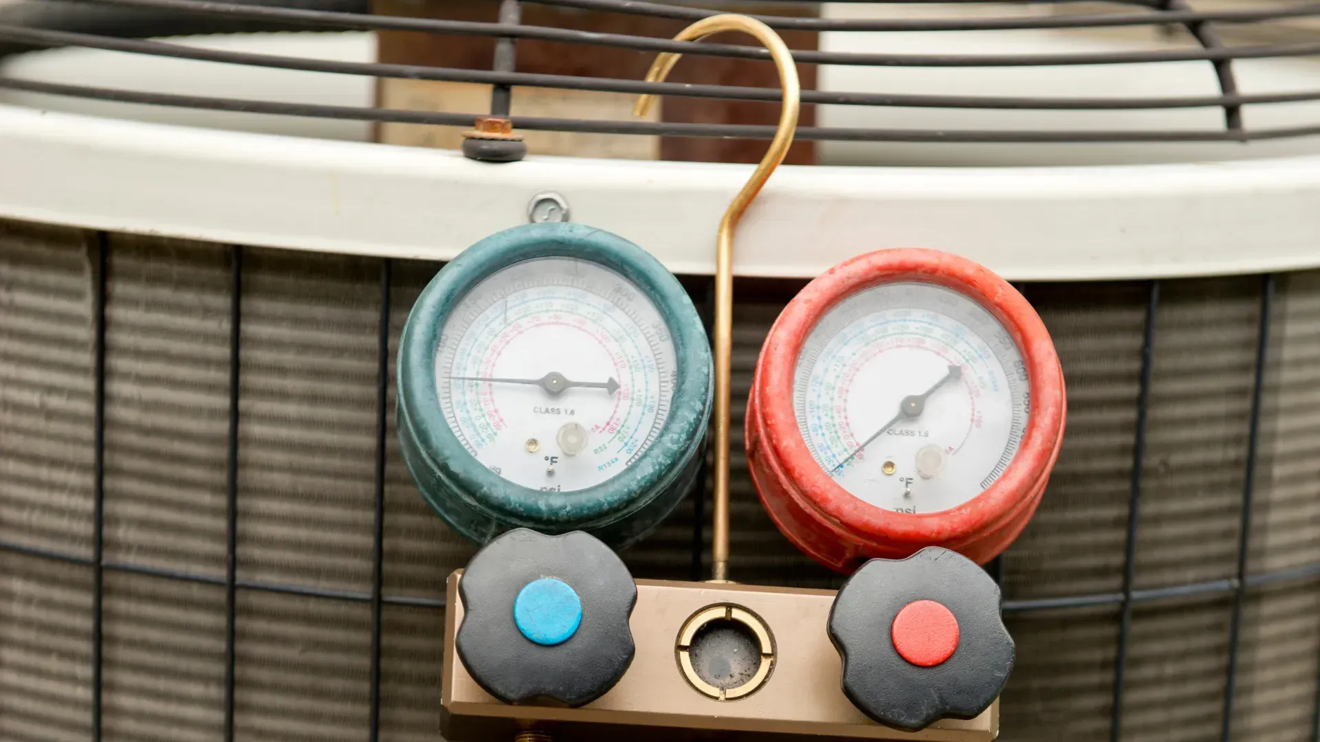 A couple of gauges are hanging on the side of an air conditioner.