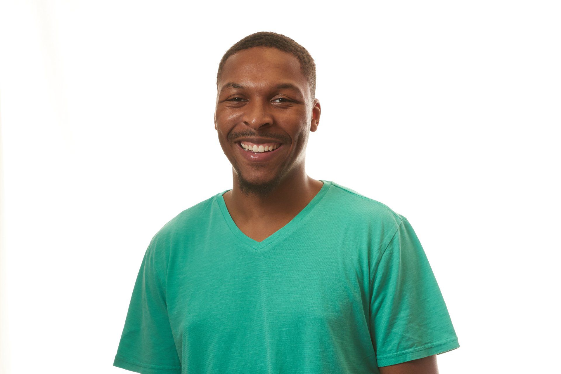 A man in a green shirt is smiling for the camera.