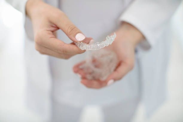 Dentist holding Invisalign clear aligners for straighter teeth treatment.