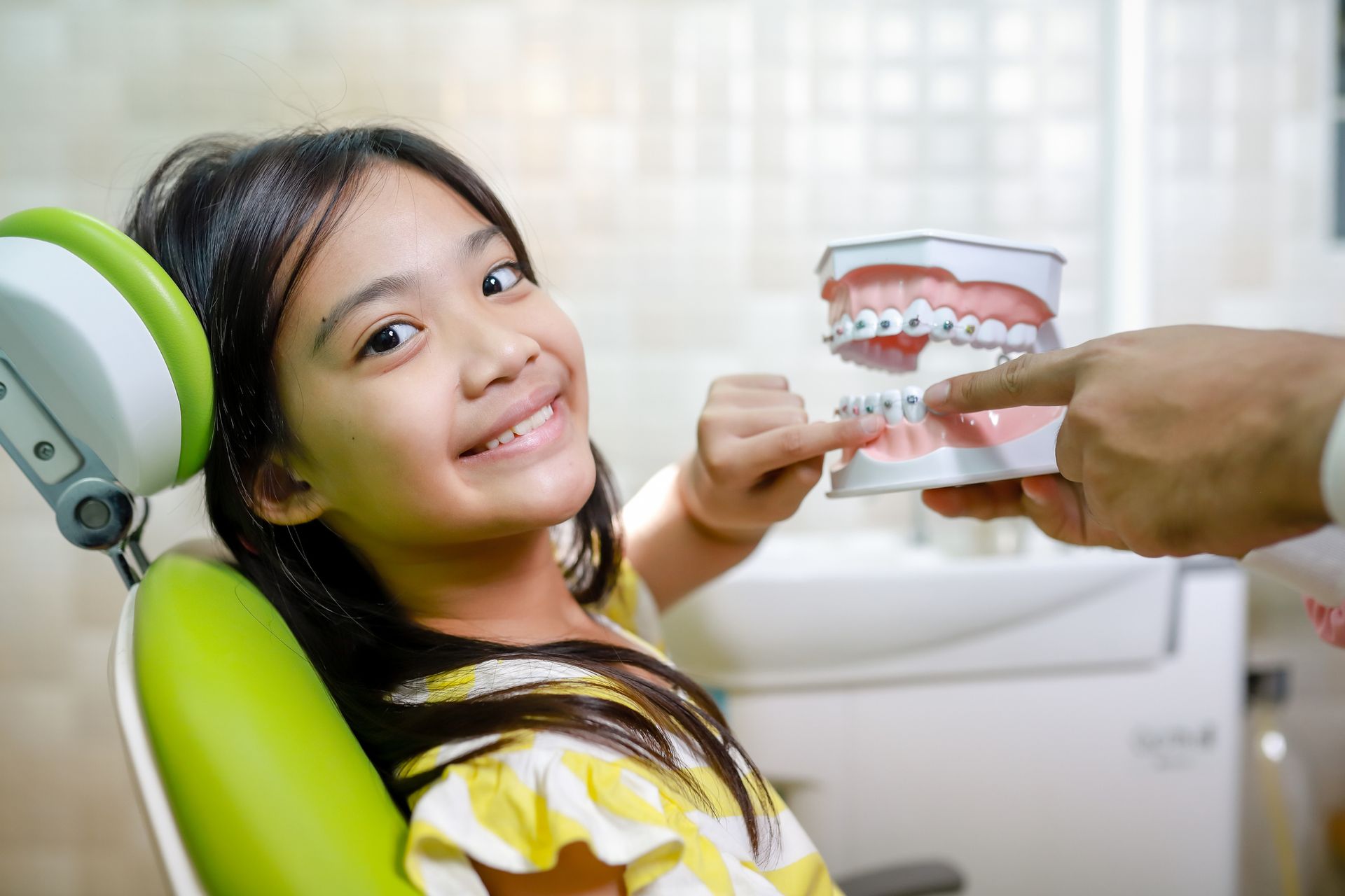 Little girl at the orthodontist looking at a braces model in Highland Park, IL
