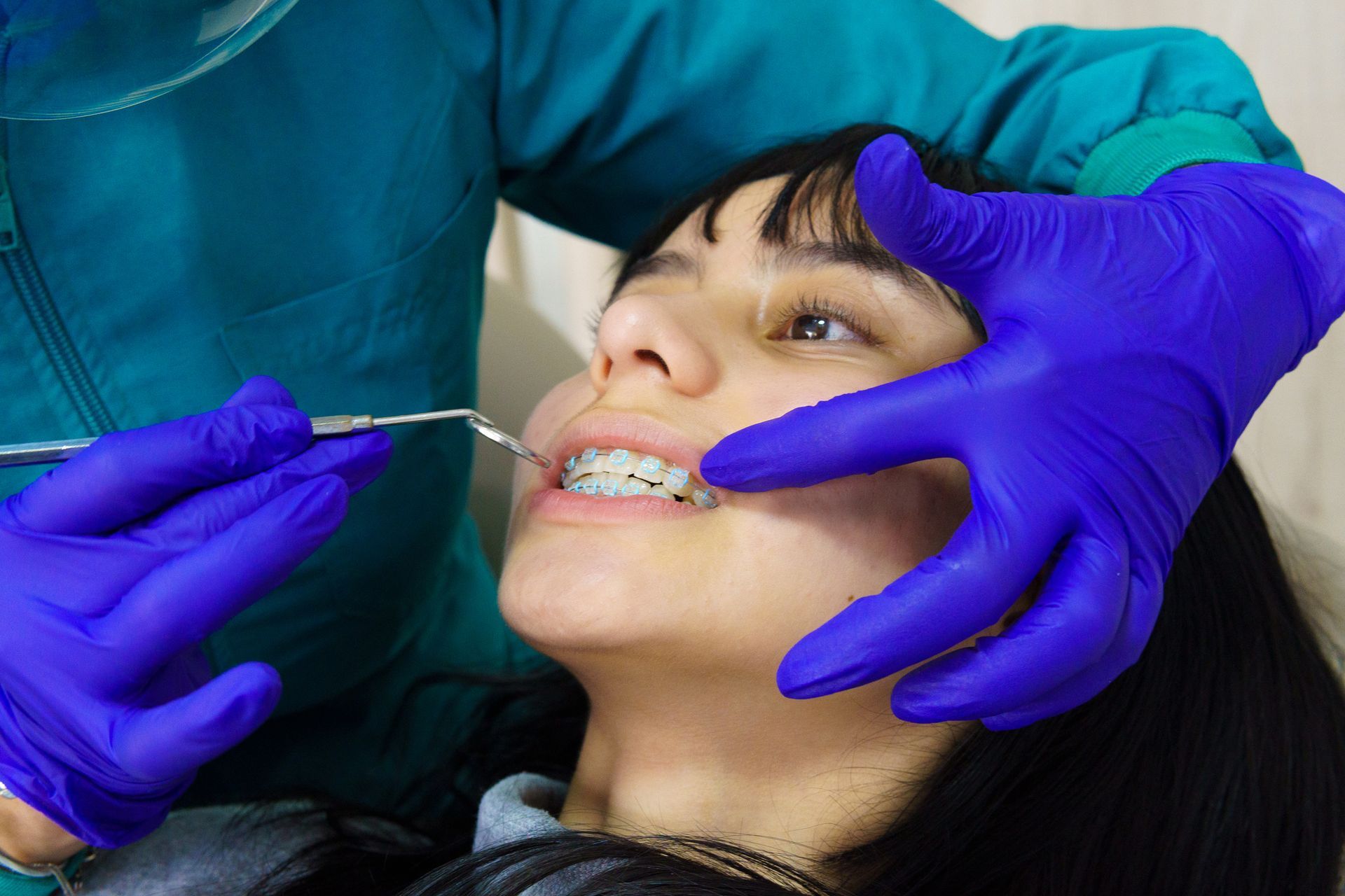 A woman is getting her braces checked by a dentist.