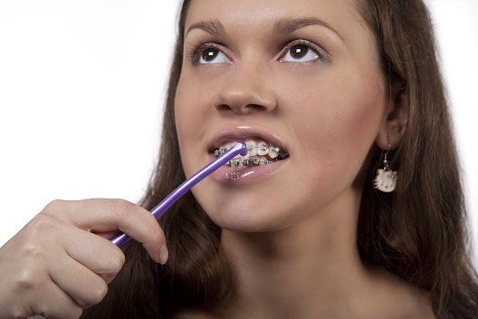 Woman using interdental toothbrush — Buffalo Grove, IL — Rosen Orthodontics