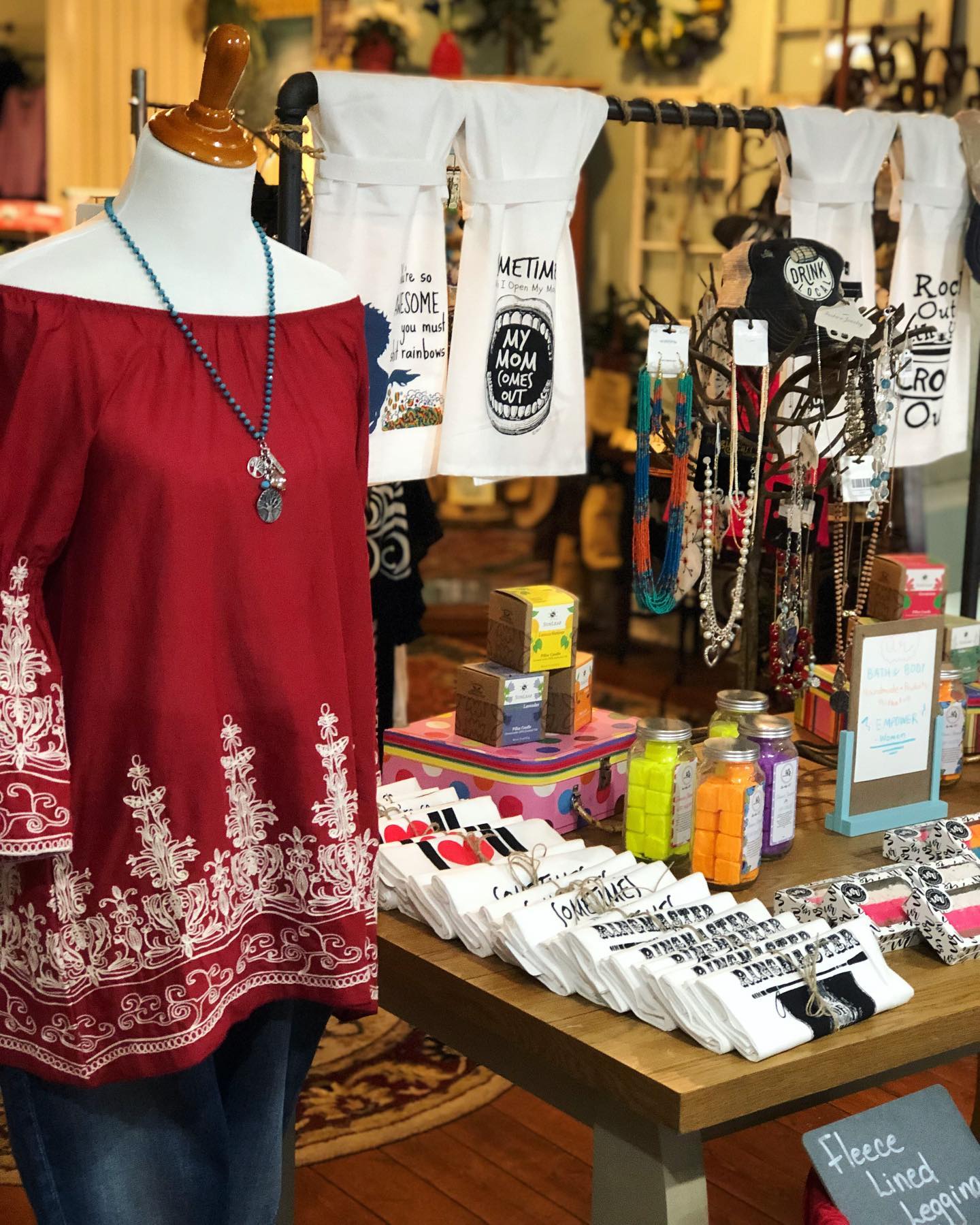 A red off the shoulder top is on a mannequin in a store.