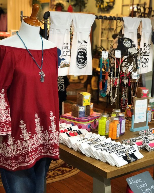 A red off the shoulder top is on a mannequin in a store.