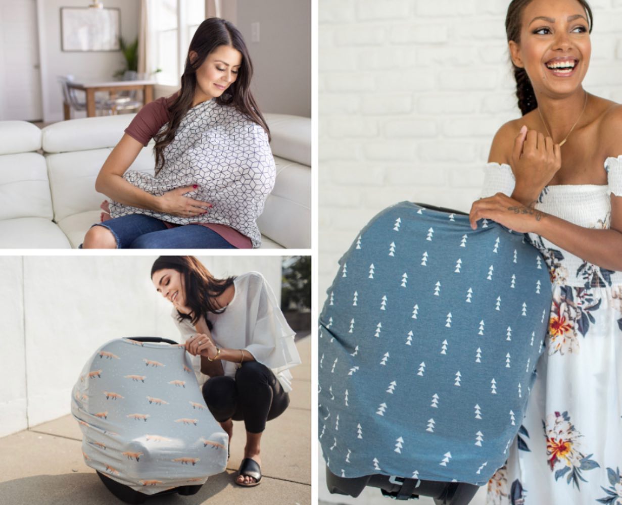 A woman is sitting on a couch holding a baby and a car seat cover.