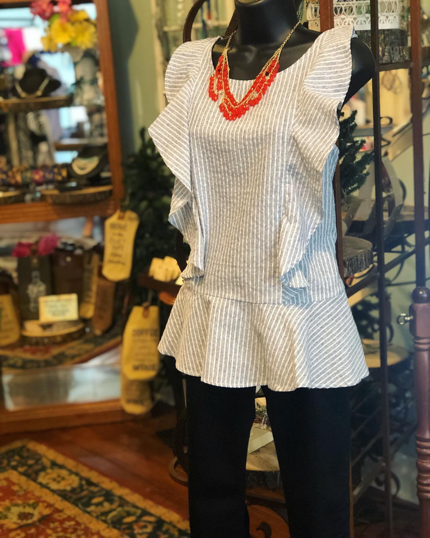 A mannequin wearing a white striped top and a red necklace