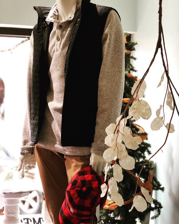 A mannequin is standing in front of a christmas tree