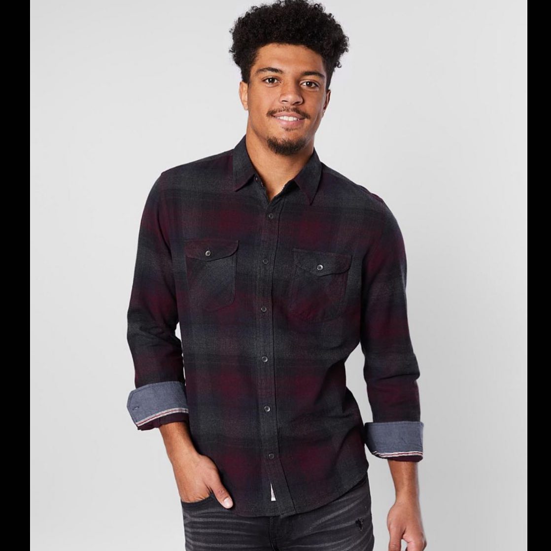 A man is wearing a plaid shirt and jeans