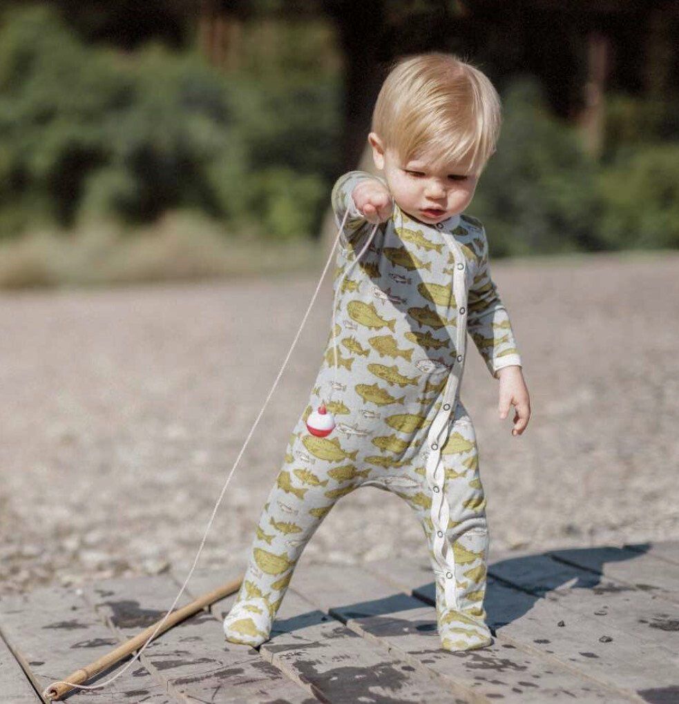 A baby in a fishing suit is holding a fishing rod.