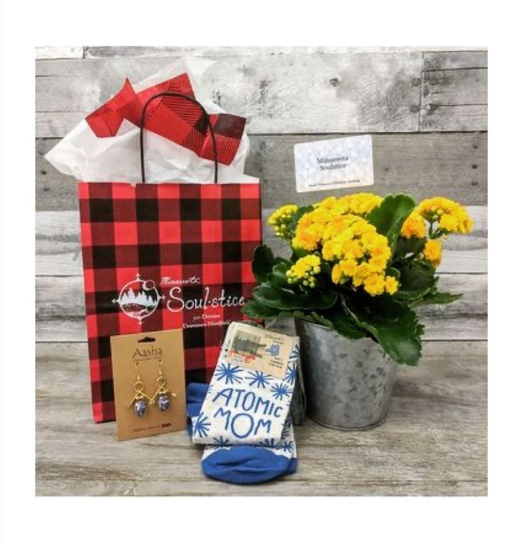 A gift bag with a plant and socks that say atomic mom